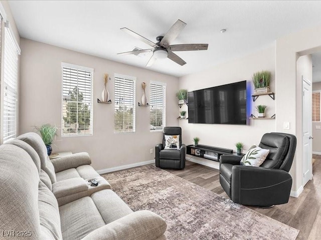 living area with baseboards, ceiling fan, and wood finished floors