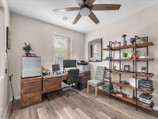 home office featuring visible vents, baseboards, light wood-style flooring, and a ceiling fan