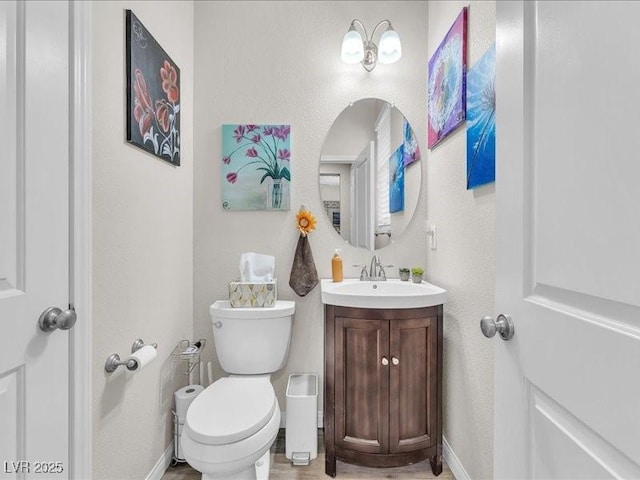 bathroom with vanity, toilet, and baseboards