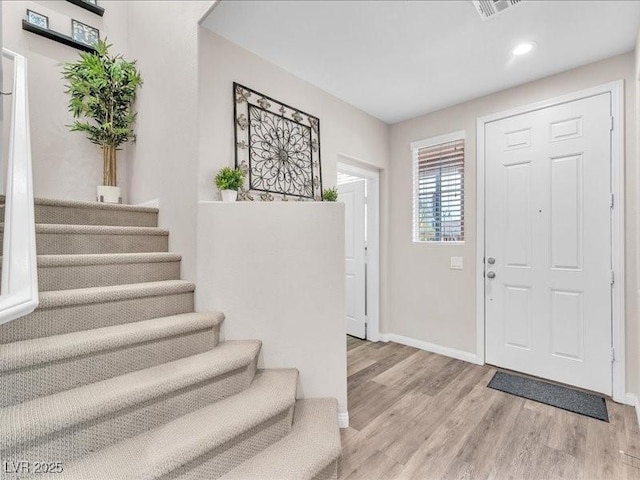 foyer entrance with stairs, wood finished floors, visible vents, and baseboards