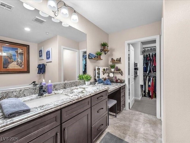 full bath featuring visible vents, a walk in closet, and vanity