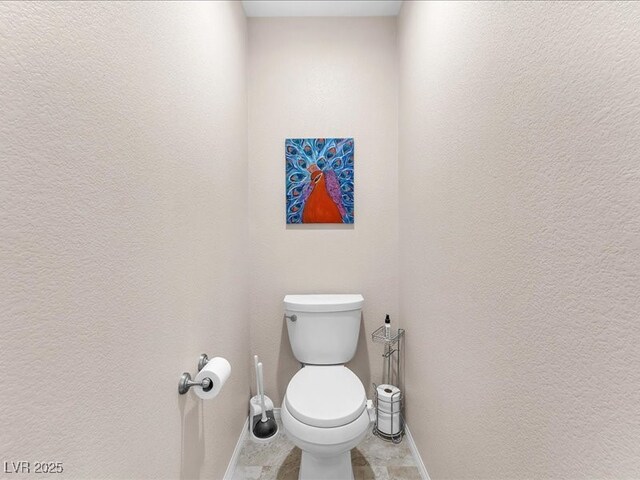 bathroom with toilet and a textured wall