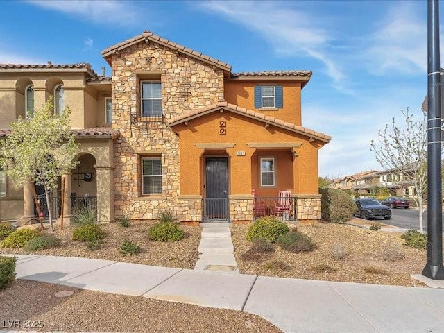 mediterranean / spanish-style home featuring stone siding and a tile roof