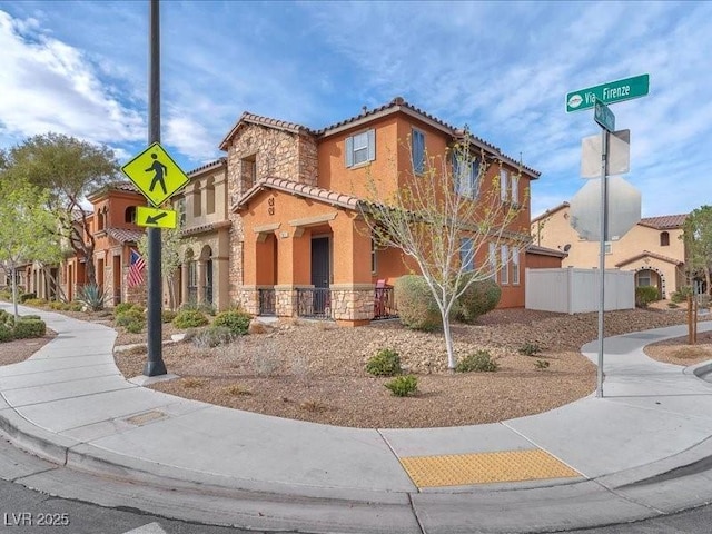 view of front of property featuring stucco siding, stone siding, a tile roof, and fence