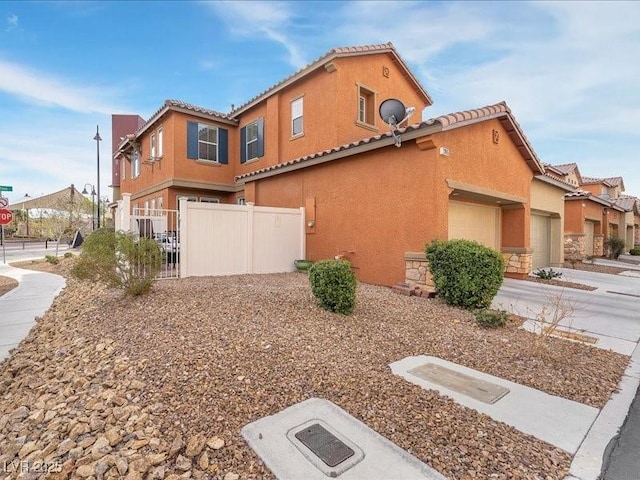 view of side of property featuring stucco siding, an attached garage, driveway, and fence