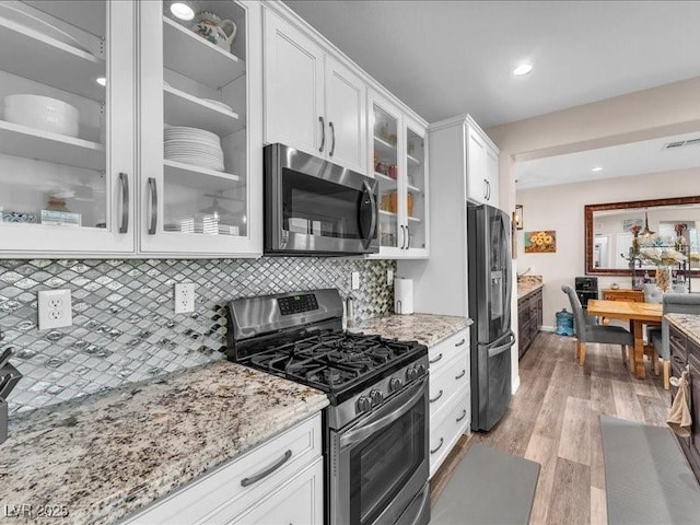 kitchen featuring visible vents, white cabinetry, light wood-style floors, appliances with stainless steel finishes, and light stone countertops