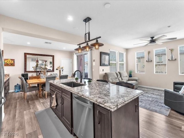 kitchen with light wood-style flooring, a sink, open floor plan, dark brown cabinets, and dishwasher