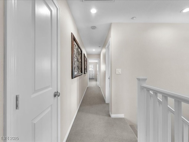 hall with recessed lighting, an upstairs landing, light colored carpet, and baseboards