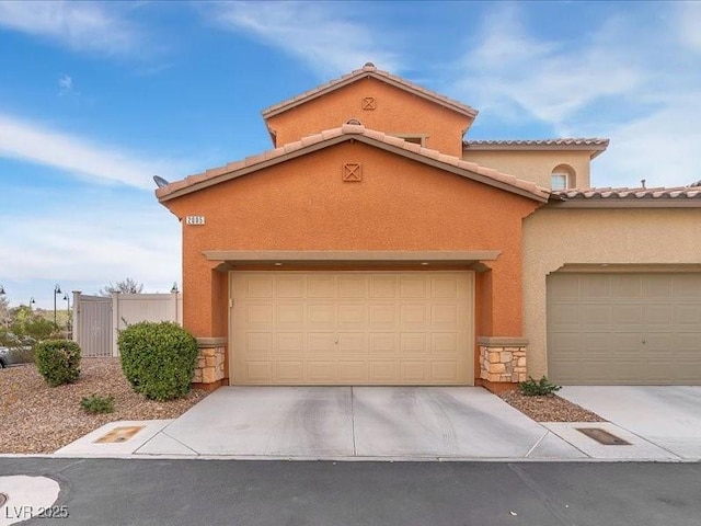 mediterranean / spanish house featuring a garage, stone siding, driveway, and stucco siding