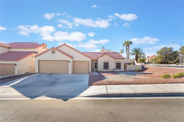 mediterranean / spanish home featuring concrete driveway, a tiled roof, an attached garage, and stucco siding