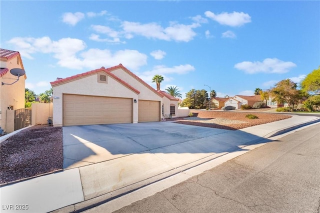 mediterranean / spanish-style house featuring an attached garage, fence, concrete driveway, a gate, and stucco siding