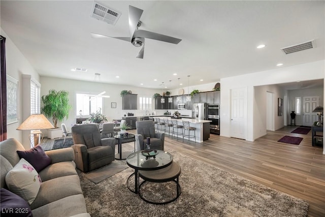 living area featuring recessed lighting, visible vents, ceiling fan, and light wood-style flooring