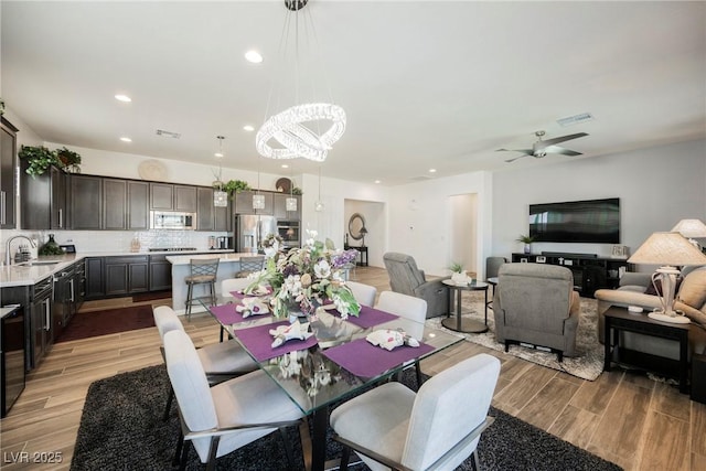 dining room with ceiling fan with notable chandelier, light wood finished floors, visible vents, and recessed lighting