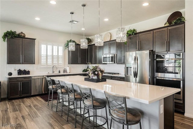 kitchen with appliances with stainless steel finishes, backsplash, dark wood finished floors, and visible vents