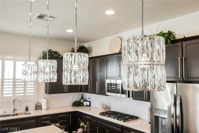 kitchen featuring visible vents, appliances with stainless steel finishes, a sink, light countertops, and backsplash