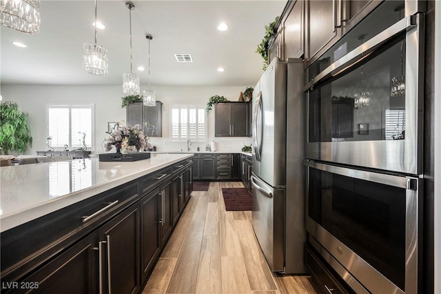 kitchen featuring stainless steel appliances, a wealth of natural light, light wood-style flooring, and visible vents