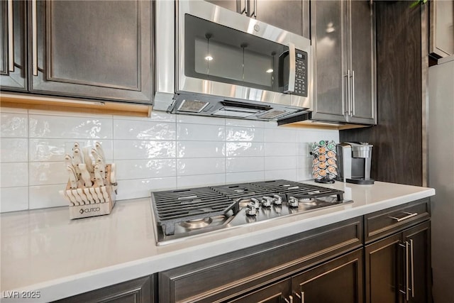 kitchen featuring stainless steel appliances, light countertops, backsplash, and dark brown cabinets