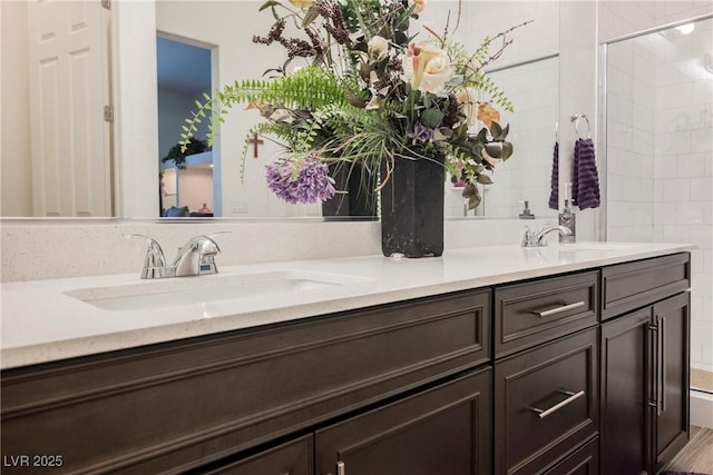 bathroom with a tile shower, double vanity, a sink, and tile walls