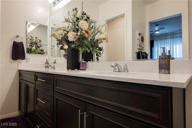 full bathroom featuring double vanity, ceiling fan, baseboards, and a sink