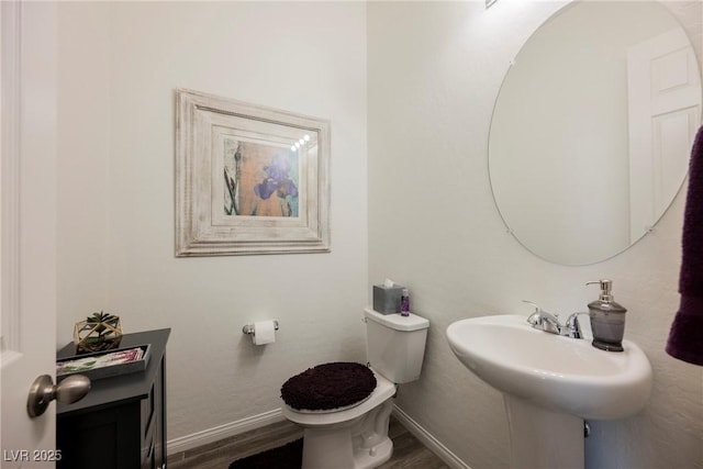 bathroom featuring baseboards, a sink, toilet, and wood finished floors