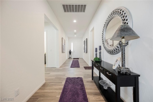 hallway with baseboards, light wood-style flooring, visible vents, and recessed lighting