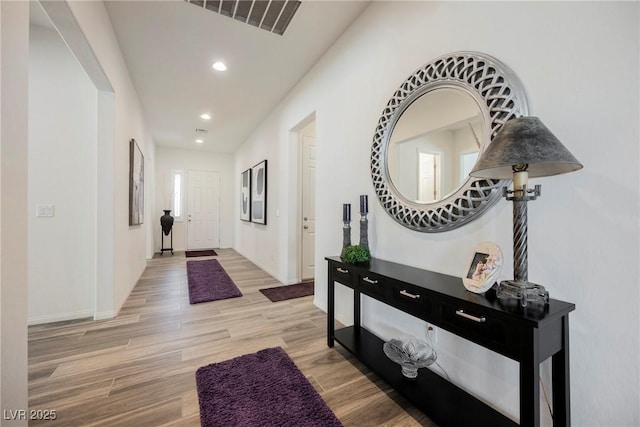 hall with baseboards, light wood-type flooring, visible vents, and recessed lighting