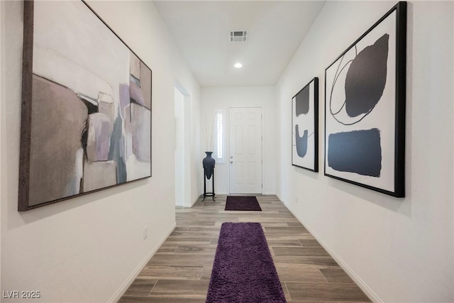 hallway featuring baseboards, visible vents, wood finished floors, and recessed lighting