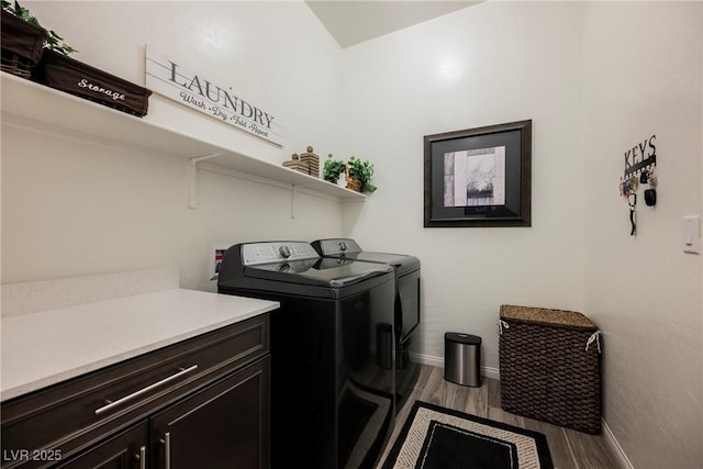 laundry room with washing machine and dryer, cabinet space, baseboards, and wood finished floors