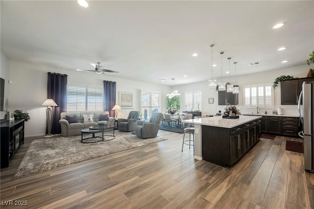 kitchen with a breakfast bar, open floor plan, wood finished floors, and a center island