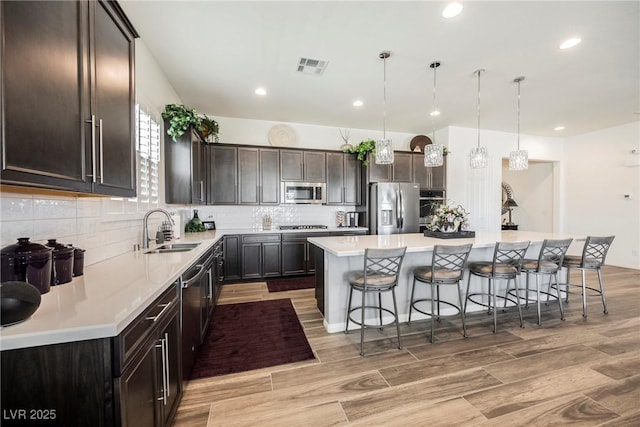 kitchen with a center island, a breakfast bar area, stainless steel appliances, visible vents, and a sink