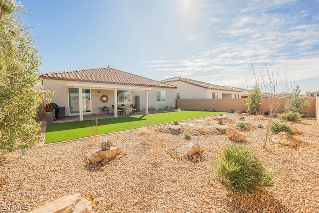 back of property featuring a lawn, a tile roof, fence, a patio area, and stucco siding