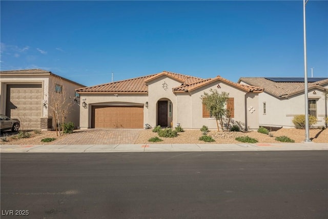 mediterranean / spanish house with a tiled roof, an attached garage, driveway, and stucco siding