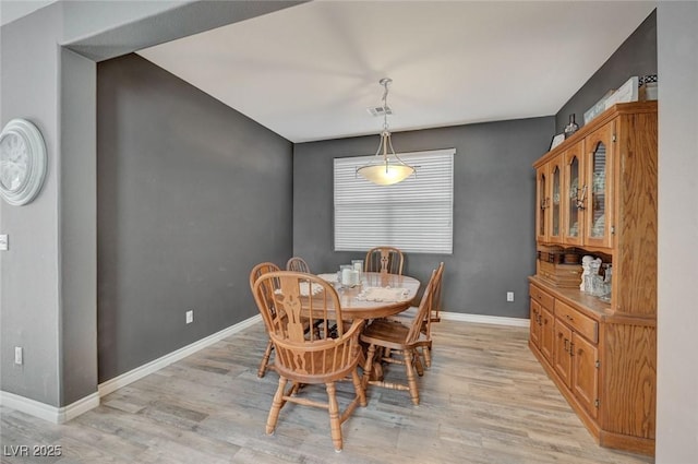 dining space featuring visible vents, light wood-style flooring, and baseboards