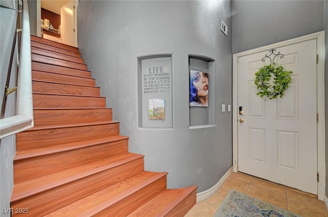 foyer with baseboards, stairway, and stone tile floors