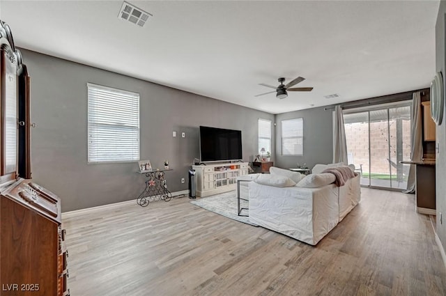 living area featuring a ceiling fan, baseboards, visible vents, and wood finished floors