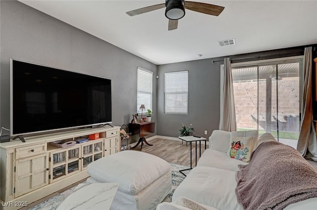 living area featuring a ceiling fan, baseboards, visible vents, and wood finished floors