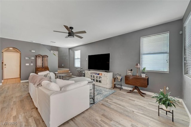 living room featuring ceiling fan, light wood finished floors, and baseboards