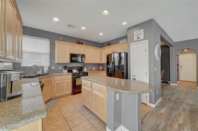 kitchen with visible vents, light brown cabinetry, a kitchen island, a sink, and black appliances