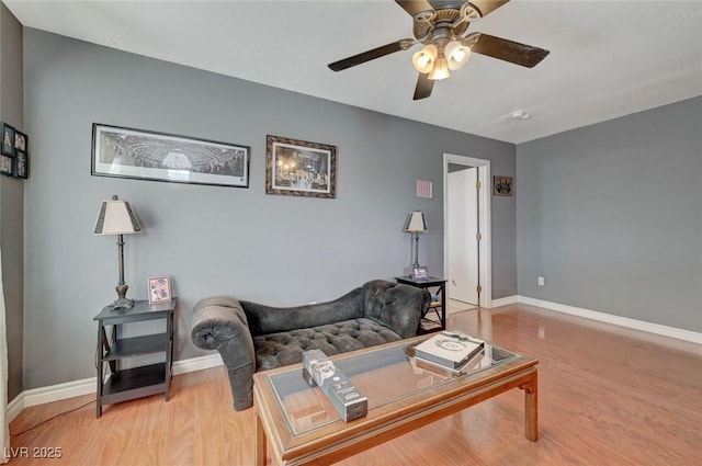 living room featuring light wood-type flooring, baseboards, and a ceiling fan