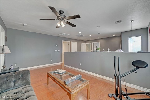 living area with wood finished floors, visible vents, and baseboards