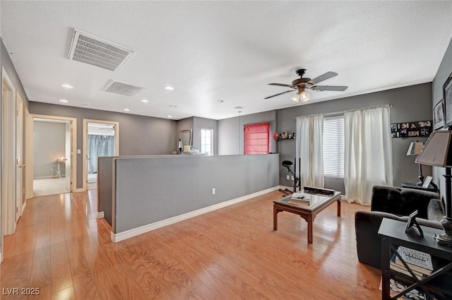 living room with light wood-style floors, plenty of natural light, and visible vents