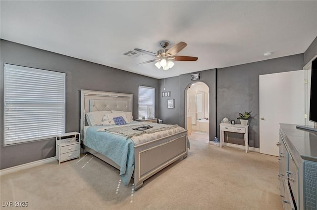 bedroom with arched walkways, baseboards, visible vents, and light colored carpet