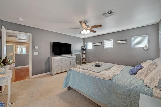 bedroom with a ceiling fan, visible vents, light carpet, and baseboards