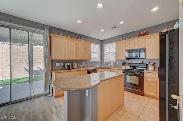 kitchen featuring black appliances, visible vents, a sink, and light brown cabinetry