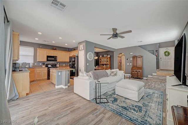 living area with arched walkways, recessed lighting, a ceiling fan, visible vents, and light wood-style floors