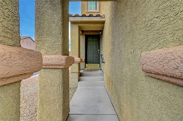 property entrance featuring a tiled roof and stucco siding