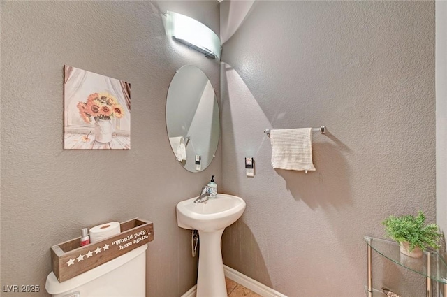 bathroom with a textured wall and toilet