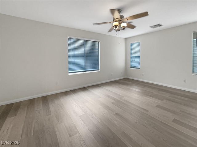 spare room featuring visible vents, ceiling fan, baseboards, and wood finished floors