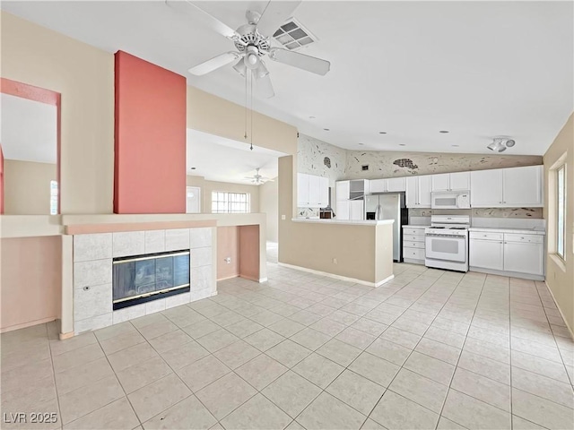 unfurnished living room with light tile patterned floors, a fireplace, vaulted ceiling, and ceiling fan