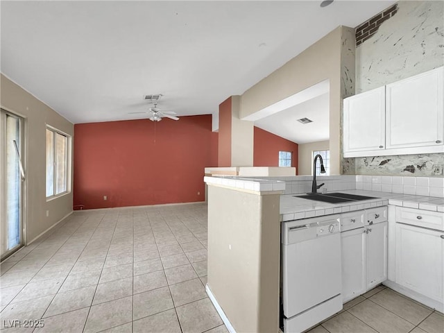 kitchen with white dishwasher, a sink, tile counters, and white cabinets